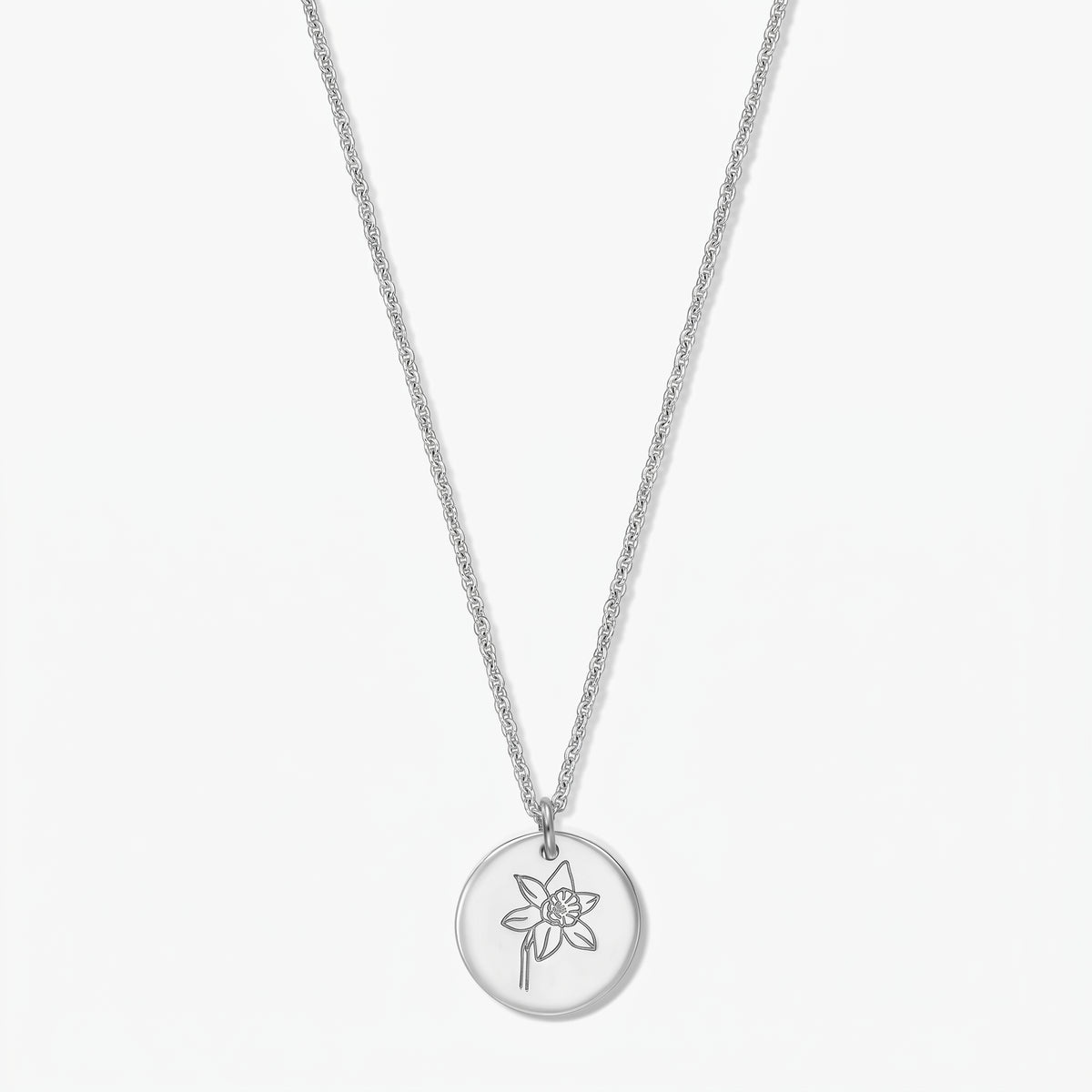 Halskette aus Sterlingsilber mit rundem Anhänger, graviert mit einer Narzisse (Geburtsblume des März), vor weißem Hintergrund.