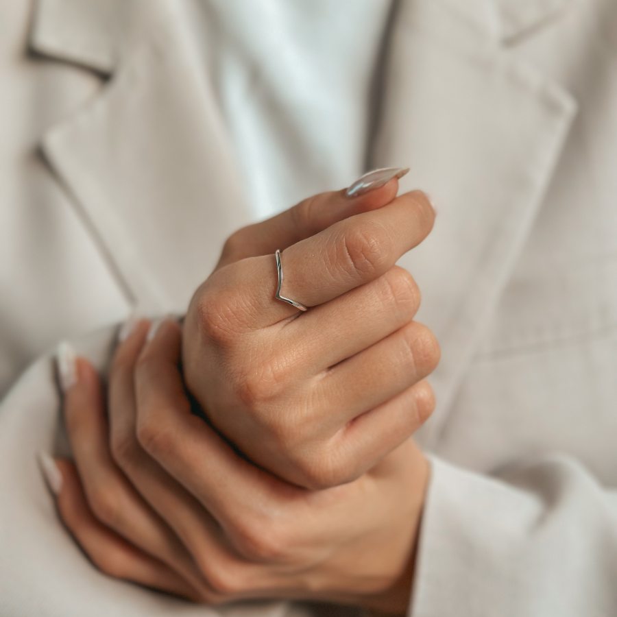 Nahaufnahme einer Hand mit einem eleganten, minimalistischen, V-förmigen Silberring.