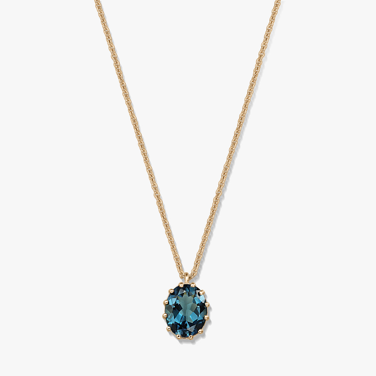 Zarte Halskette aus vergoldetem Sterlingsilber mit ovalem Anhänger aus London Blue Topas auf weißem Hintergrund.