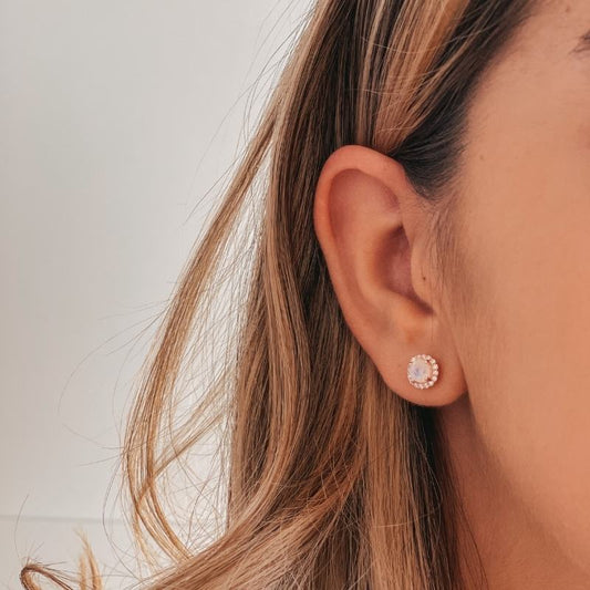 Nahaufnahme des Ohrs einer Person mit einem Keira Rose Silberohrring mit Mondstein vor hellem Hintergrund.