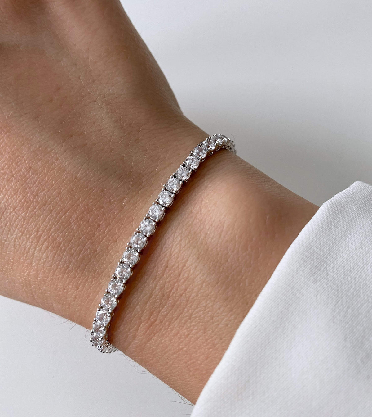 Nahaufnahme eines Handgelenks, das ein silbernes Tennisarmband mit Zirkonia-Steinen trägt.