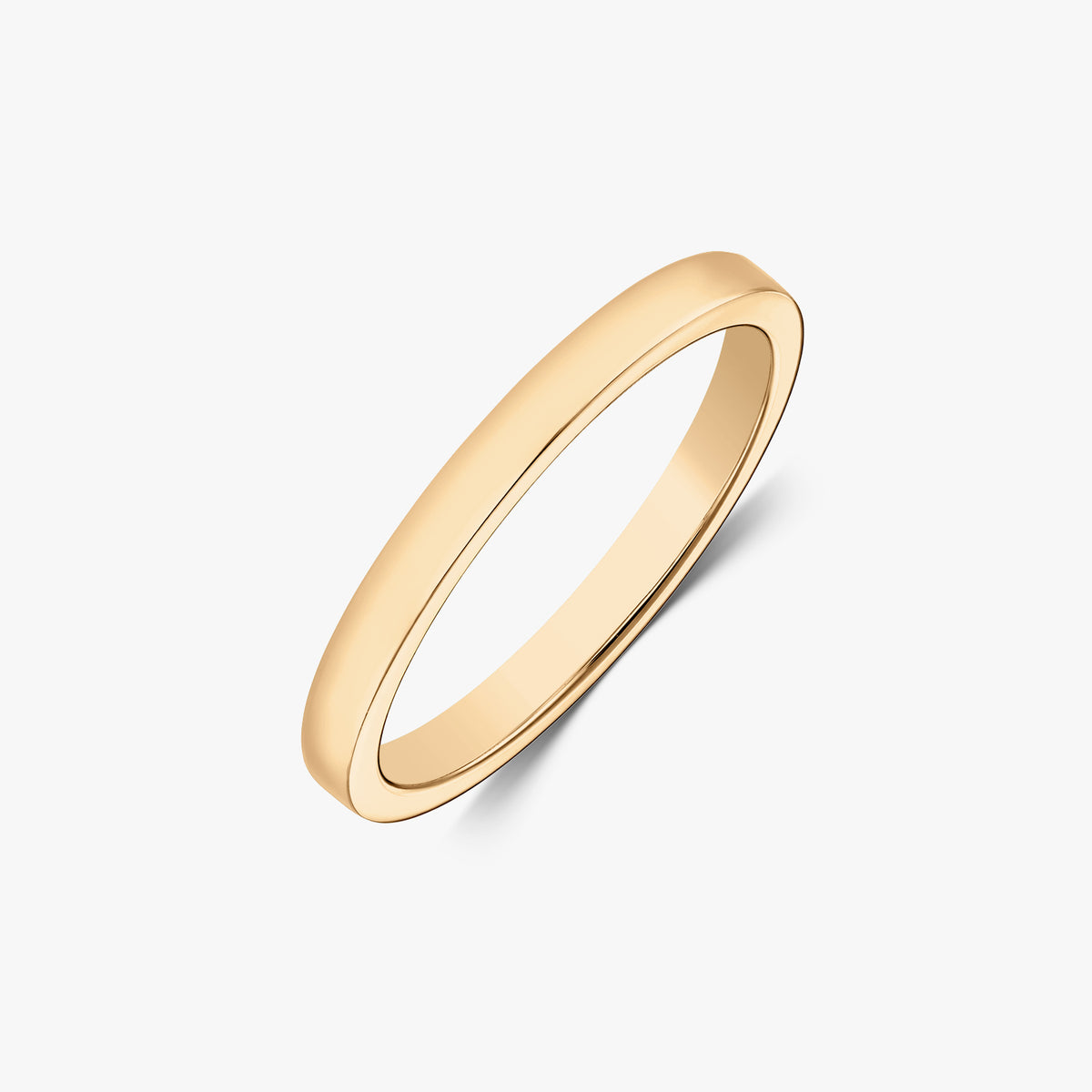Schräg aufgenommene Studioaufnahme eines schlanken, polierten Bandrings aus 14k Gelbgold vor weißem Hintergrund.