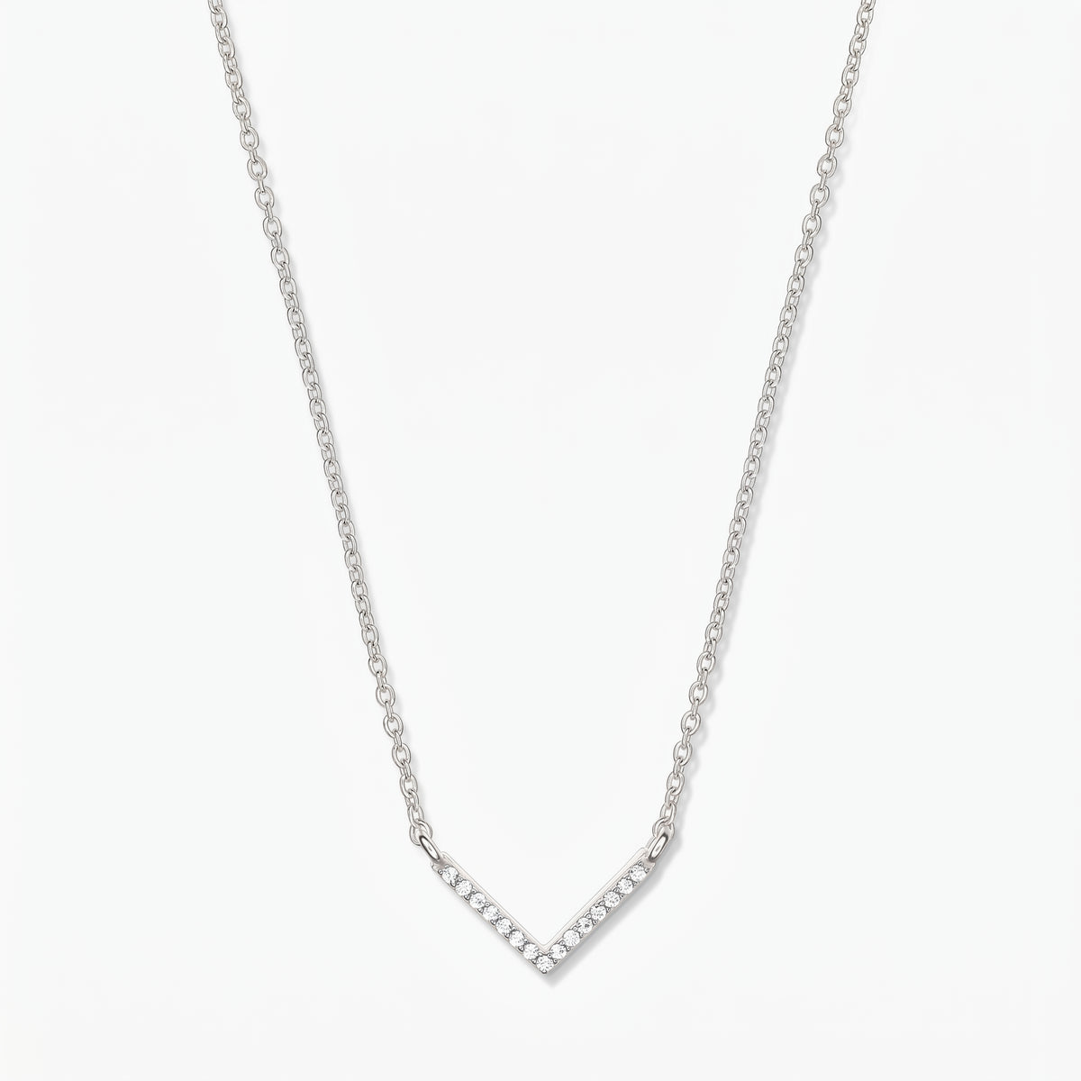 Silberne V-förmige Zirkonia-Halskette mit zarter Kette und pavébesetztem Chevron-Anhänger auf weißem Hintergrund.