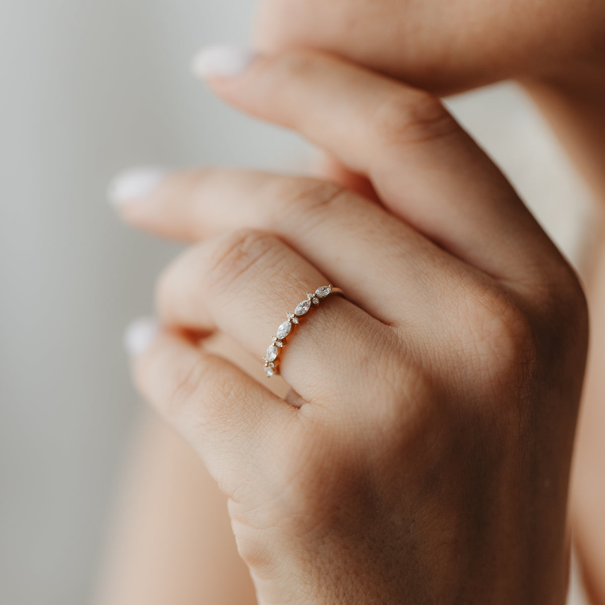 Nahaufnahme einer Hand mit dem Fiorelle-Diamantring aus Gelbgold, besetzt mit abwechselnden Marquise- und Rundschliffsteinen.