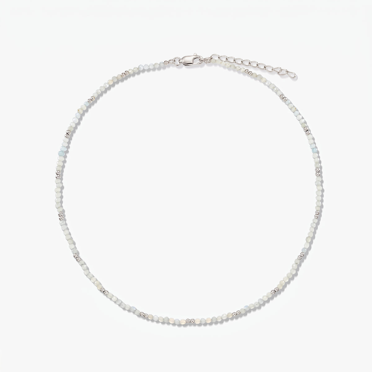 Zarte Halskette aus Sterlingsilber mit kleinen Mondsteinperlen und verstellbarer Verlängerungskette, auf weißem Hintergrund fotografiert.