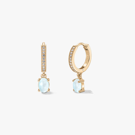 Indira Golden Gem Huggies Silberohrringe mit ovalen Mondstein-Tropfen und pavé-besetzten Creolen, vorne und seitlich vor weißem Hintergrund dargestellt.