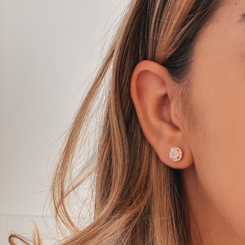 Nahaufnahme des Ohrs einer Person mit einem Keira Rose Silberohrring mit Mondstein vor hellem Hintergrund.
