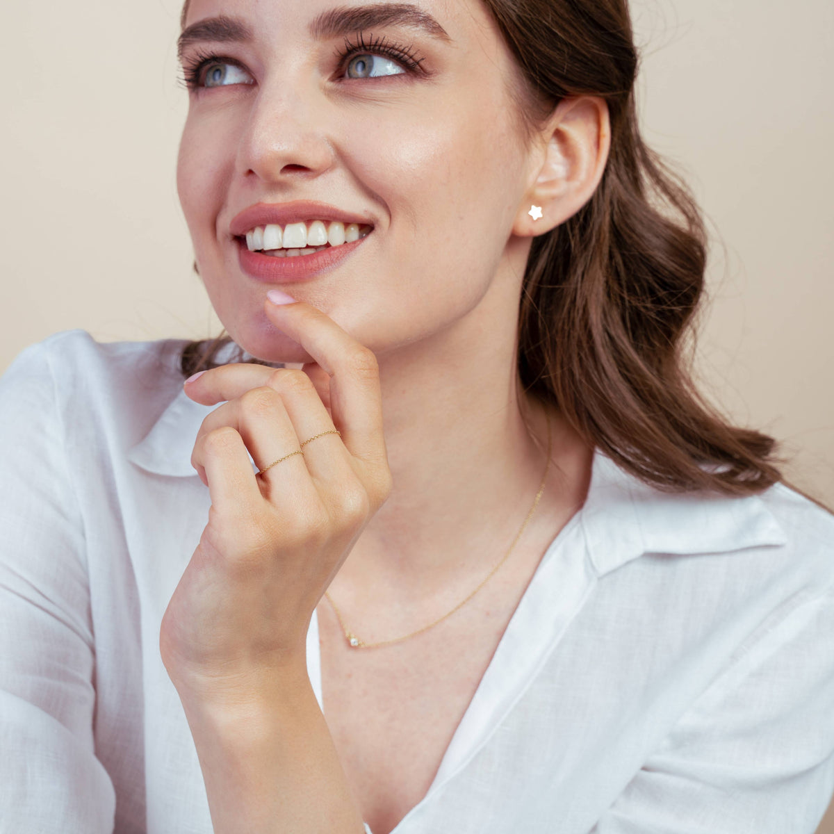 Lächelnde Frau mit einem 14K-Gold-Kettenring und einem sternförmigen Ohrring.